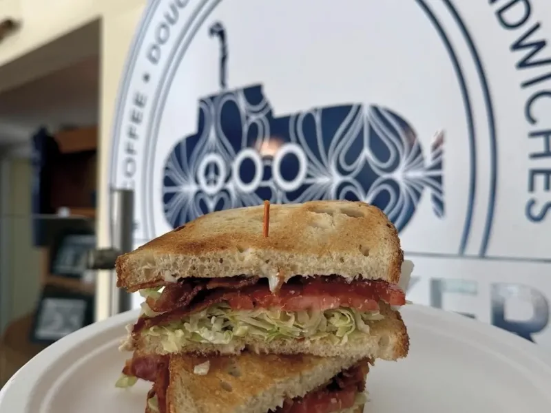 A toasted BLT cut in half on a paper plate