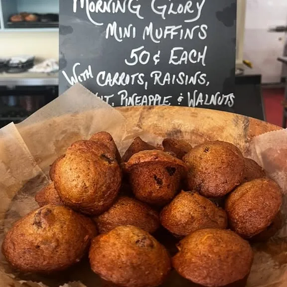 A basket of Morning Glory mini muffins under a handwritten chalkboard sign