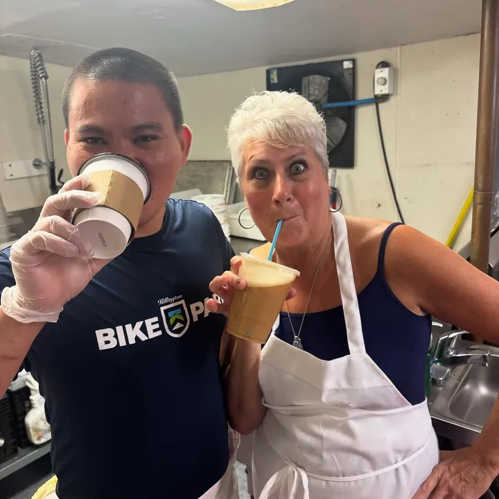 Two staff members taking a coffee break behind the counter